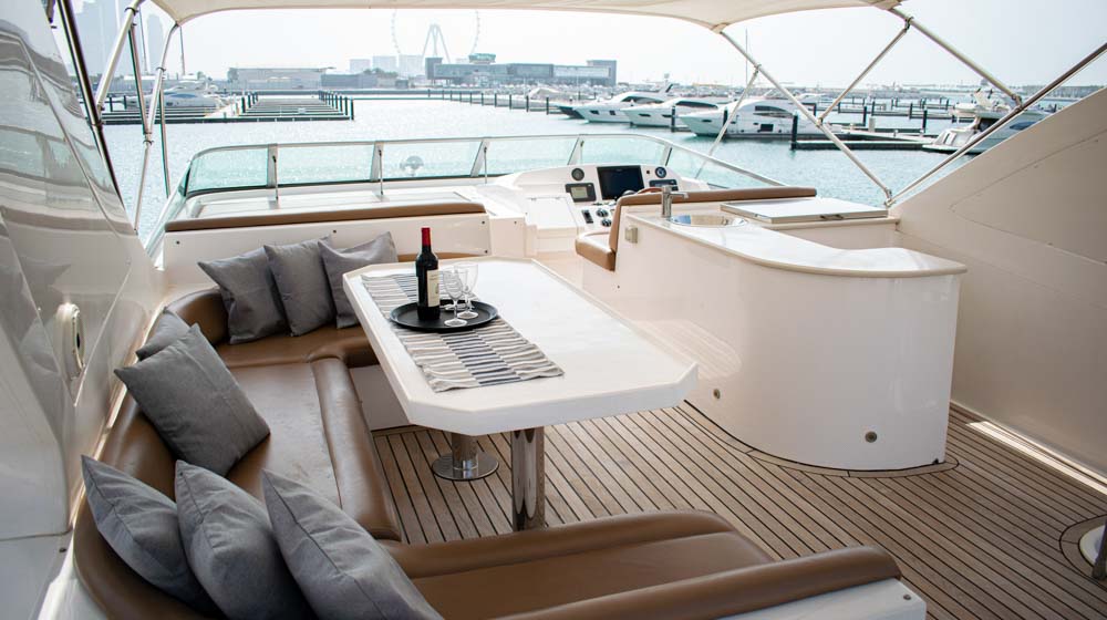 flybridge of yacht featuring dining aboard with leather seating, red wine bottle, electric bbq, control station